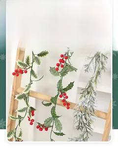 Close-up of artificial Christmas vine with holly leaves, red berries and frosted pine needles