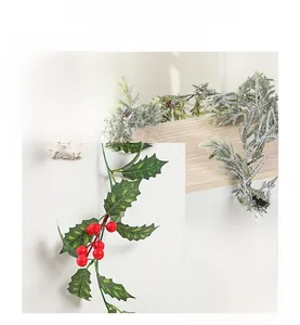 Detailed view of artificial Christmas garland with red berries and snowy pine needles