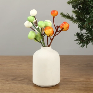 Artificial berry branches in a minimalist white ceramic vase for home christmas decor