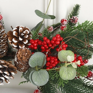 Christmas wreath decoration with snowy pinecones, red berries, and green eucalyptus leaves