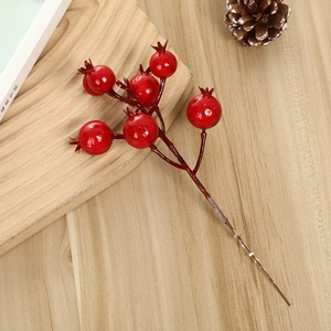 Detailed view of glossy red berry stems on a natural wood surface for festive decor