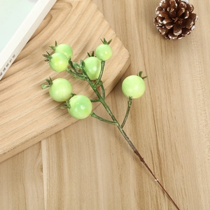 Detailed close-up of realistic light green artificial foam berries on dark brown branch