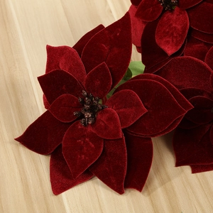 Close-up of red velvet artificial Christmas poinsettia with realistic flocked texture
