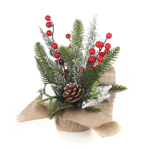 Miniature Christmas tree with red berries, pine cones and snow in a rustic burlap base