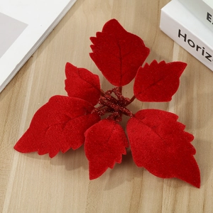 Velvet red artificial poinsettia flower with glitter center on light wood background