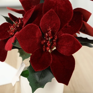 Artificial red poinsettia Christmas potted plant with velvet petals in a white ceramic pot
