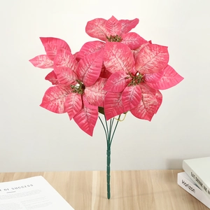 Detailed view of pink artificial poinsettia stems on a wooden table with decor