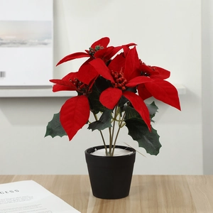 Close-up of artificial poinsettia with vibrant red petals and green leaves in a black pot