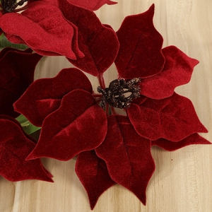 Deep red velvet artificial poinsettia flower for Christmas decoration on wood background