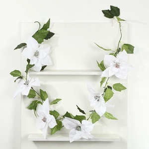 Detail of artificial white poinsettia garland with green leaves for holiday wall decor