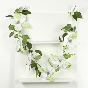Detail of artificial white poinsettia garland wrapped on a white minimalist shelf