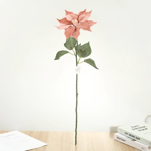 Détail d'un poinsettia artificiel rose avec pétales soyeux et feuilles sur table en bois