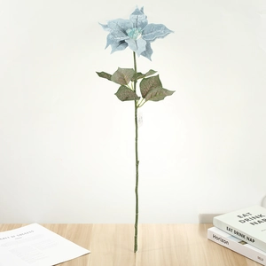 Détail d'un poinsettia artificiel bleu clair avec pétales veloutés sur bois