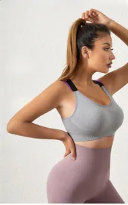 Detail of wide black shoulder straps on a gray sports bra and purple high-waist yoga pants