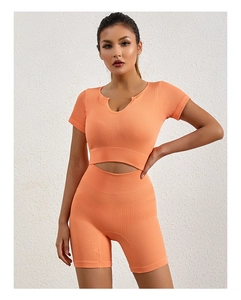 Dettaglio completo sportivo a coste arancione con scollatura unica e pantaloncini yoga a vita alta