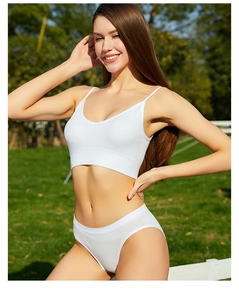 Détail d'un ensemble de lingerie en coton côtelé blanc sur fond d'herbe ensoleillée