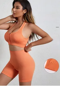 Dettaglio dei pantaloncini biker arancioni e del reggiseno sportivo con zip frontale