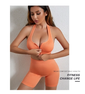 Dettaglio macro del set fitness arancione a costine con zip frontale e pantaloncini