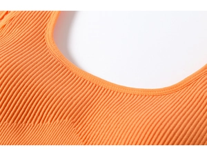Macro detail of bright orange ribbed sports bra fabric with precise U-neckline stitching