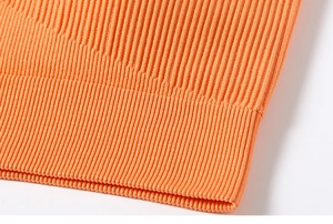 Macro detail of the high-elasticity orange ribbed knit fabric and seamless hem texture