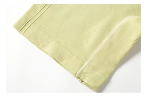 Close-up of light green ribbed fabric with professional white overlock stitching detail