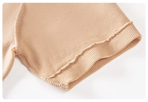 Macro detail of apricot knit sleeve featuring textured waffle weave and ruffled edges
