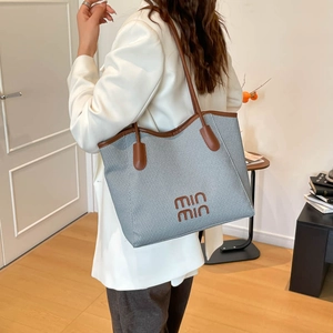 Retro grey woven tote bag with brown leather trim shown on shoulder in daily setting