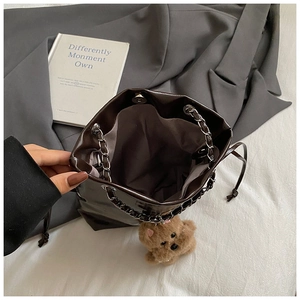 Détail intérieur du sac seau marron brillant avec bandoulière chaîne et breloque peluche