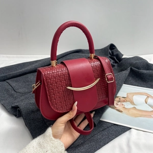 Detail of red leather saddle bag with woven texture lid and golden crescent buckle