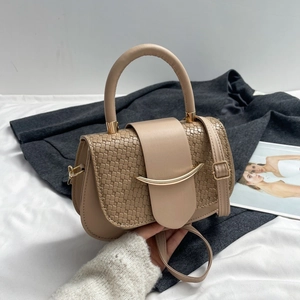 Detail of khaki saddle bag with woven texture panel and golden metallic hardware accent