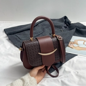 Detail of dark brown woven saddle bag with gold metal buckle and leather handle