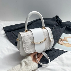 Close-up of white woven checkered saddle bag featuring gold hardware and flap closure