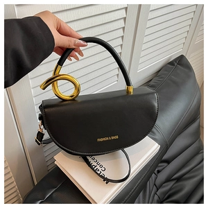Detail of black leather half-moon bag featuring unique spiral gold handle and logo
