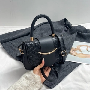 Detail of black faux leather saddle bag with embossed croc flap and gold crescent buckle
