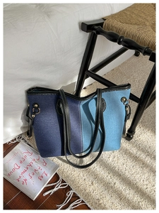 Détail du sac cabas en denim bicolore avec garnitures en cuir noir et boucles dorées