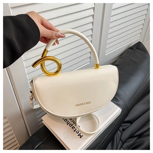 Close-up of cream white saddle bag featuring elegant gold knot hardware on the handle