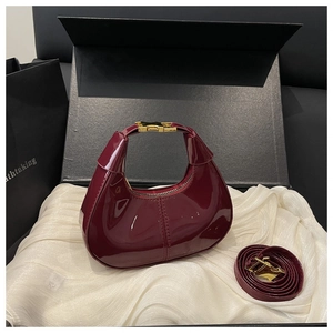 Détail du sac hobo en cuir verni bordeaux avec boucle en métal doré et fermeture éclair