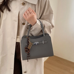 Elegant grey leather top-handle square bag with metallic buckle and woven charm