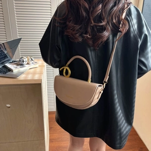 Chic beige half-moon saddle bag with golden knot hardware for minimalist fashion style