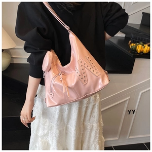 Detail van roze laksleren hobo-tas met metalen klinknagel N-logo en kleine ronde portemonnee