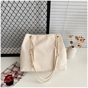 Dettaglio della borsa tote color crema in pelle martellata con manici a catena oro