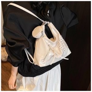 Detail van een witte glanzende hobo-tas met zilveren klinknagels en een ronde kleine tas