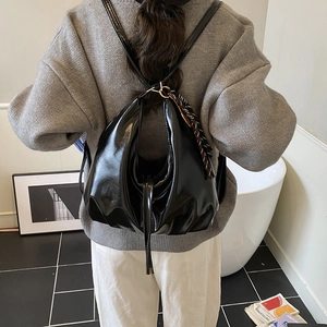 Mochila chic de charol negro con detalle de pañuelo de seda en modelo femenina