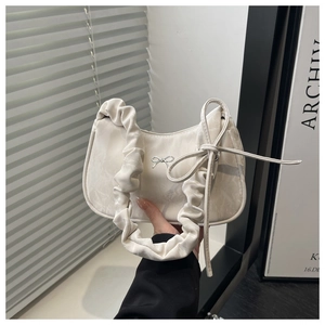 Détail du sac à bandoulière plissé blanc crème avec boucle papillon argentée et pompon doux