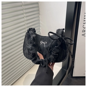 Détail du sac à bandoulière noir froncé avec boucle papillon argentée et bandoulière plissée