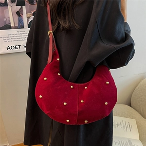 Deep red velvet crescent tote bag with gold studs and adjustable shoulder strap
