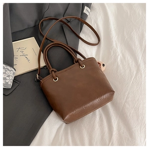 Dettaglio borsa tote in ecopelle marrone scuro con finiture dorate su sfondo morbido