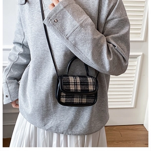 Detailed view of mini plaid crossbody bag with leather handle worn by a model