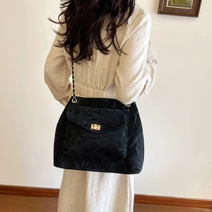 Borsa a spalla nera alla moda con trama a pieghe e catena dorata su modella femminile