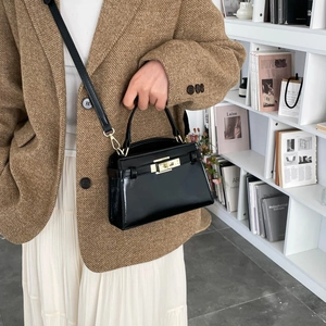 Sac à main Kelly élégant en cuir crocodile noir avec boucle dorée porté par un mannequin